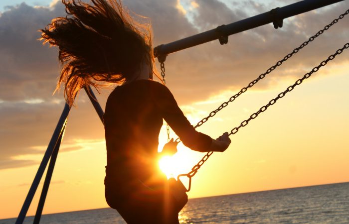 woman riding on swing during sunset